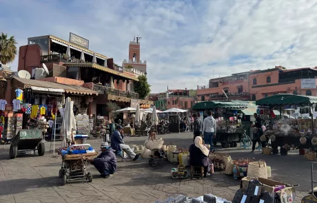 A photograph of Jemaa el-fnaa square in Marrakesh, Morocco showing the bustle of people, traders and tourists