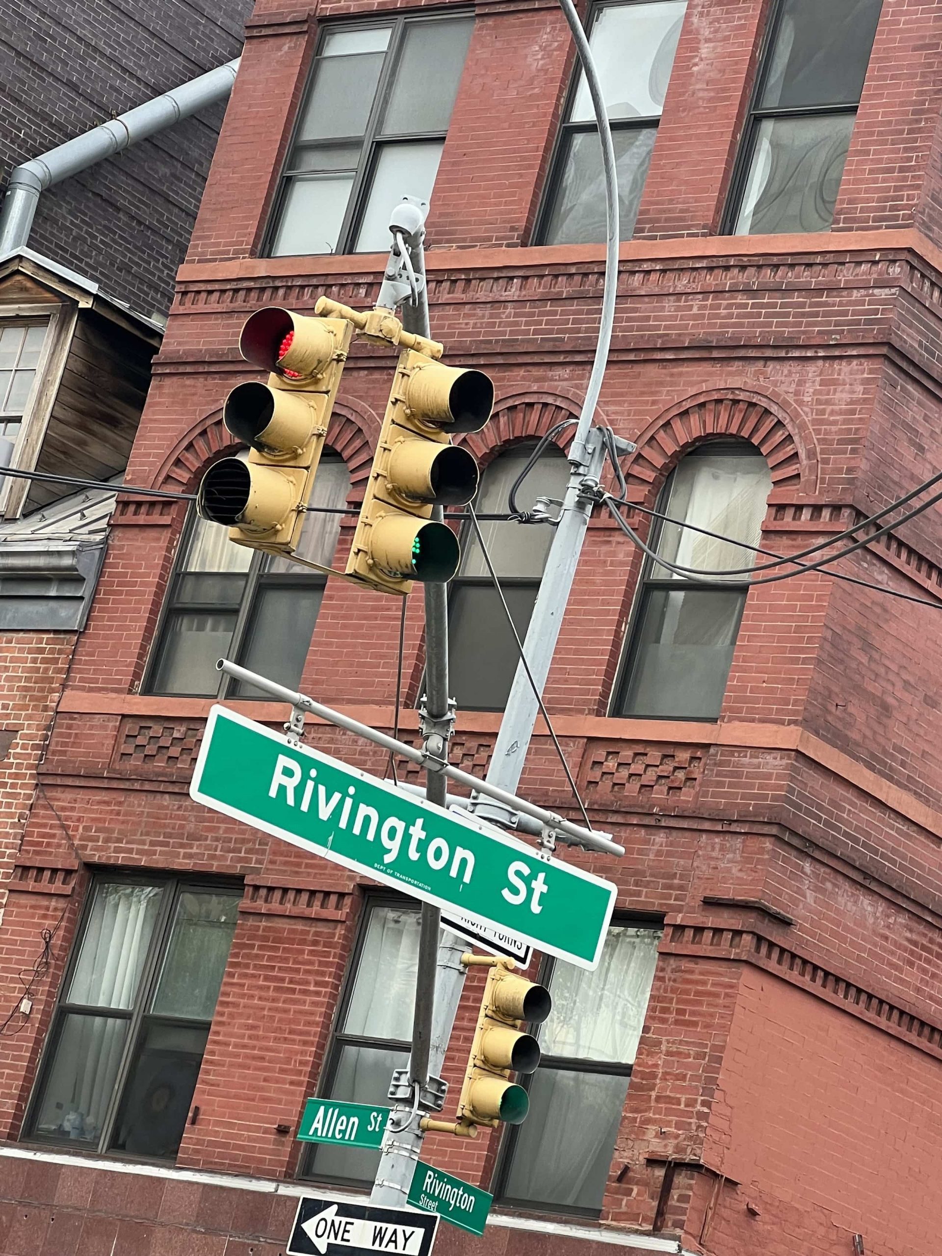 East_Coast_Roadtrip_New_York_00020 A green Street sign depicting Rivington St in New Yorks lower east side hanging below a yellow traffic light infront of a red brick building