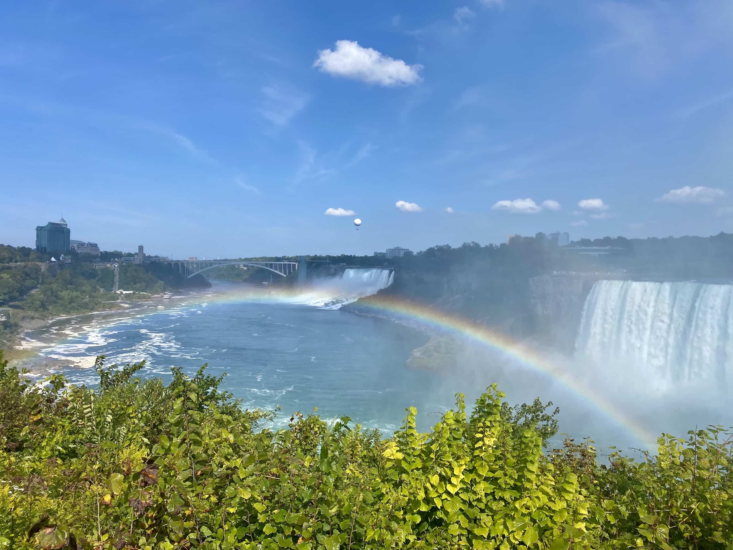 East_Coast_Roadtrip_Niagara_00003 a rainbow over Niagara River with th erainbow bridge in the background and American Falls and Bridal Veil falls to teh right