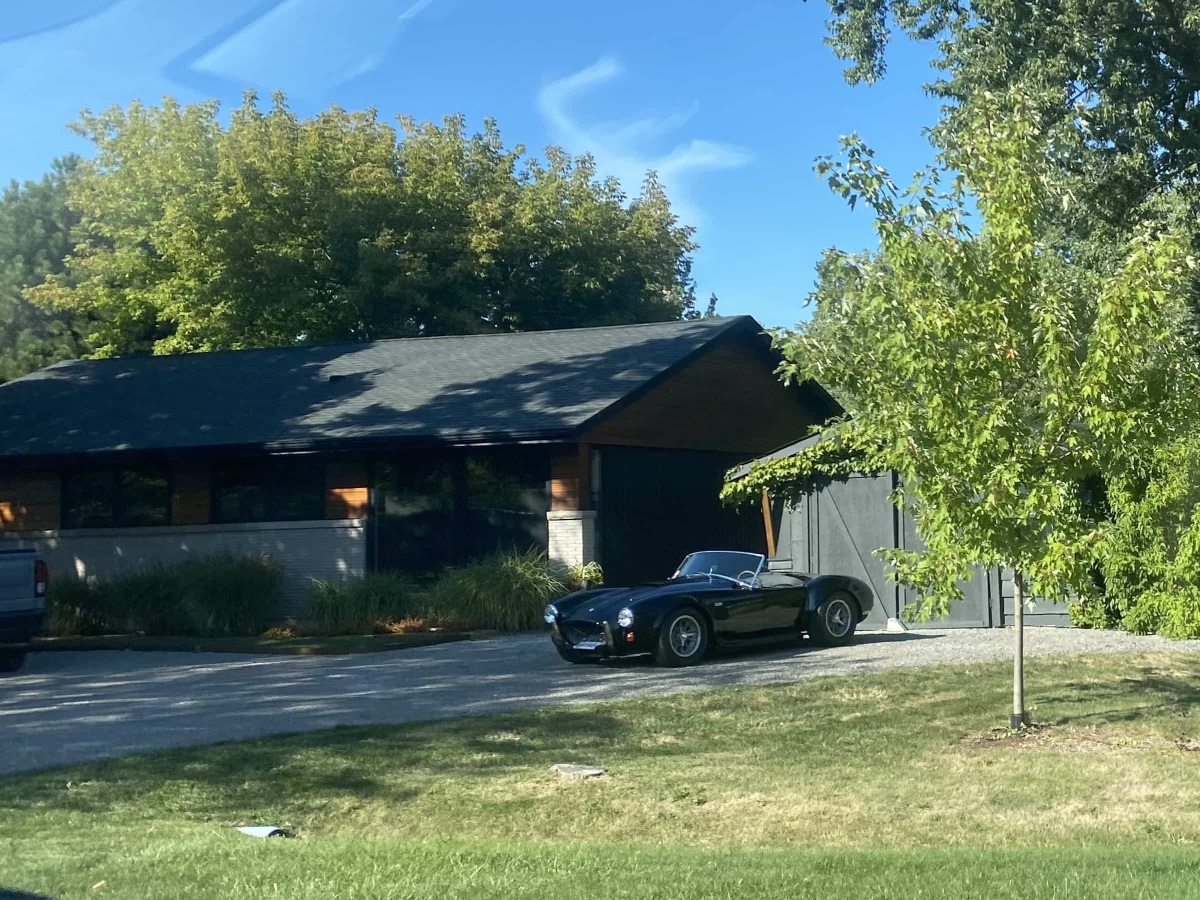 East_Coast_Roadtrip_views_from_passenger_side_gallery_01-00042 A black AC Cobra sports car sitting in fron of a garage on a residential drive